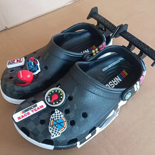 Black nascar crocs clogs with racing-themed stickers on a brown surface