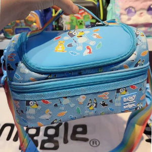 Blue lunch bag with cartoon designs held by a hand, on a colorful background.