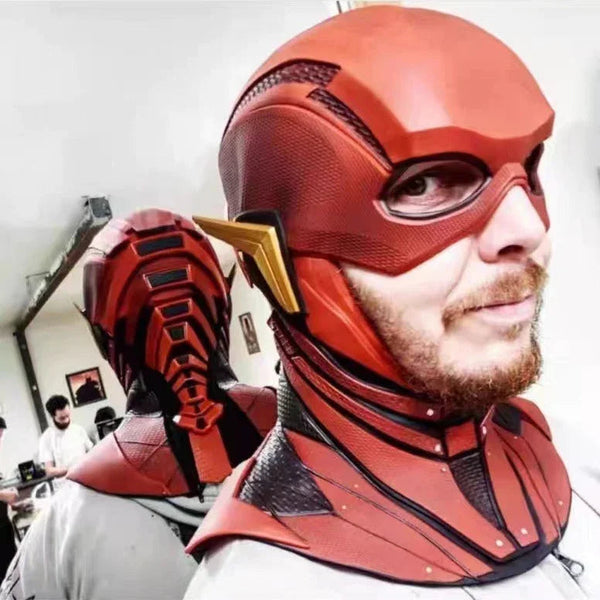 Person wearing a flash costume with a helmet, with another person adjusting the helmet in a workshop setting.